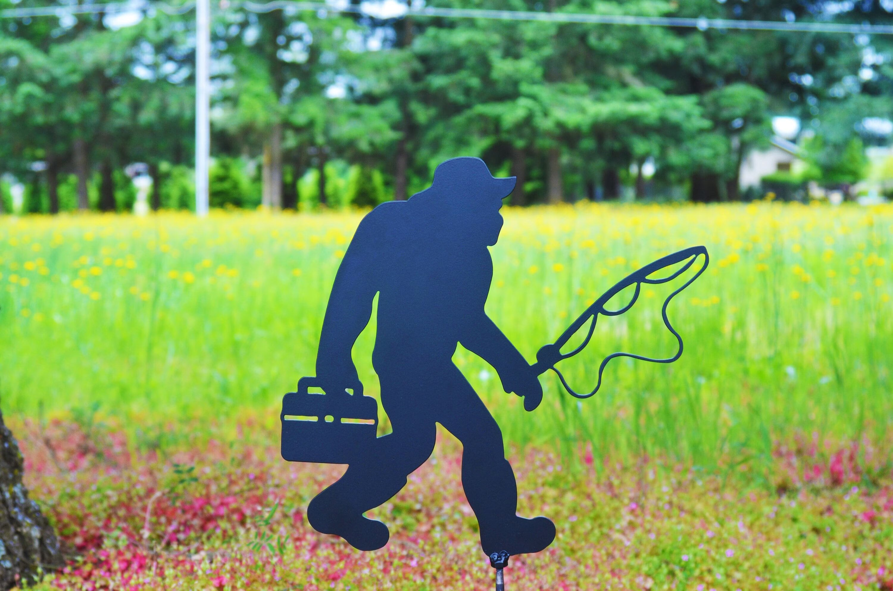 Bigfoot fishing with a fishing pole and tackle box and fishing bucket hat and weighter fly fishing shoes